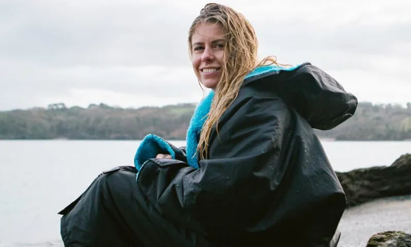 Girl sat outside wearing Dryrobe after cold water swimming